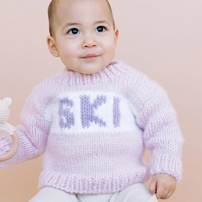 Baby wearing a pink knitted sweater with &