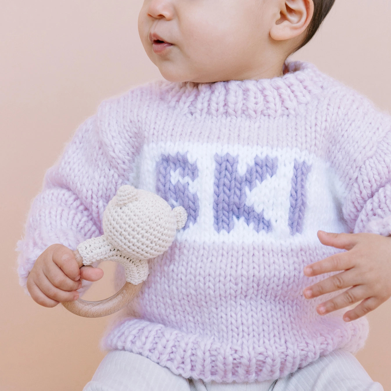 Baby wearing a pink knit sweater with &