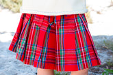 Red plaid skirt worn by a person with a blurred natural background