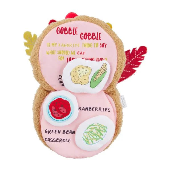 Plush toy shaped like a turkey with food-themed buttons on a white background