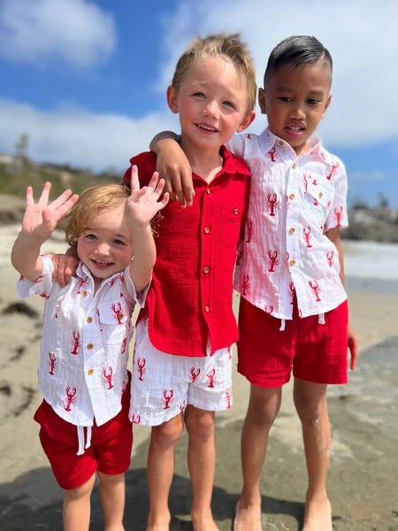 Three children in matching outfits on a beach