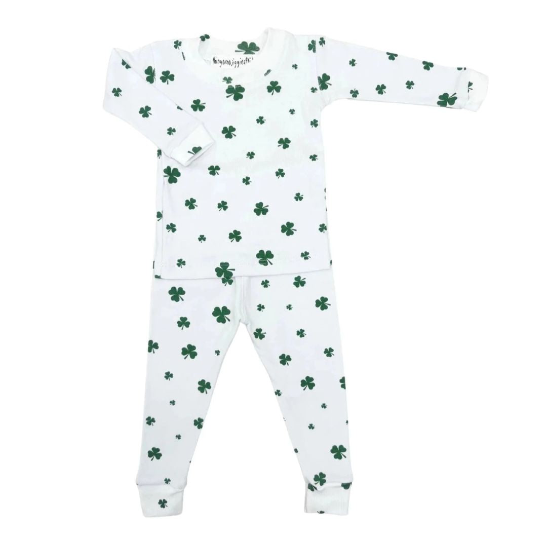 A baby long-sleeve pajama set with a white base and green shamrock pattern, laid flat on a white background.