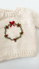 cream sweater with wreath on it