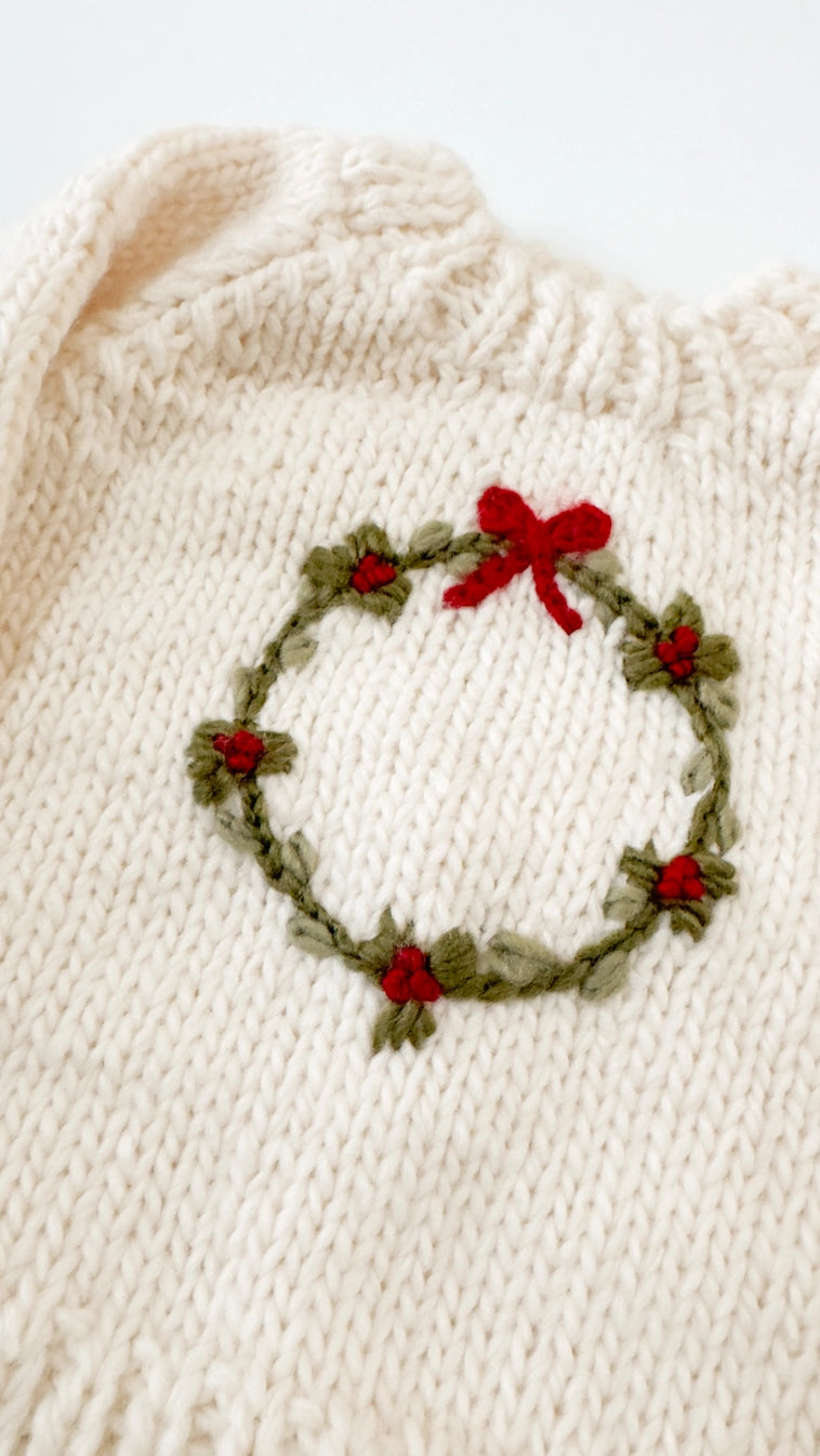 cream sweater with wreath on it