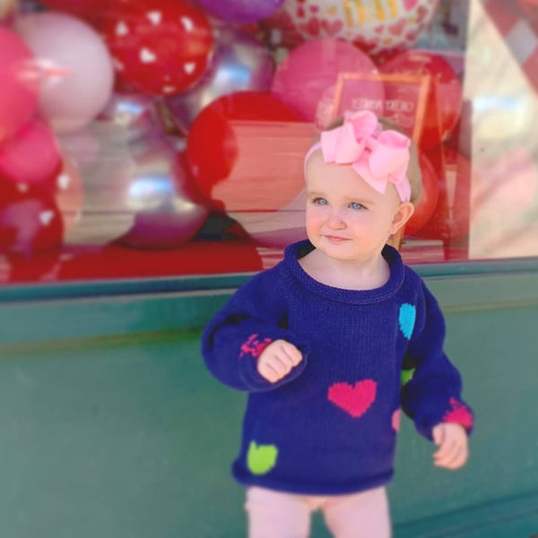 baby girl wearing Navy Hearts Roll Neck Sweater with pink leggings and pink hair bow