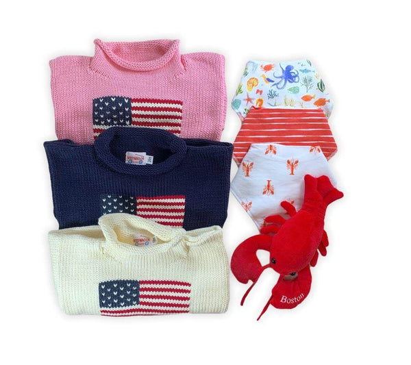 pink, navy and ivory roll neck sweaters laid out with matching bibs and a lobster plush