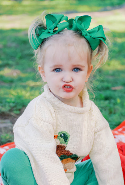 toddler wearing sweater with green bows in her hair