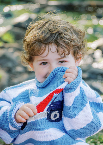 boy wearing blue striped dump truck sweater