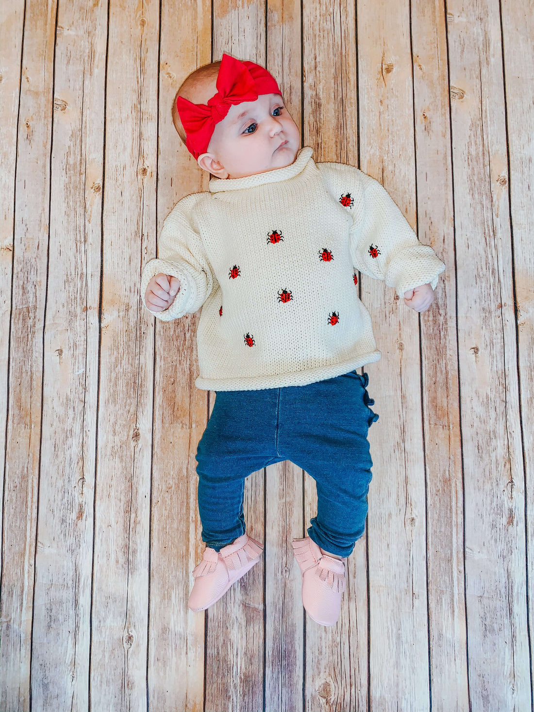 baby girl wearing ivory ladybug roll neck sweater
