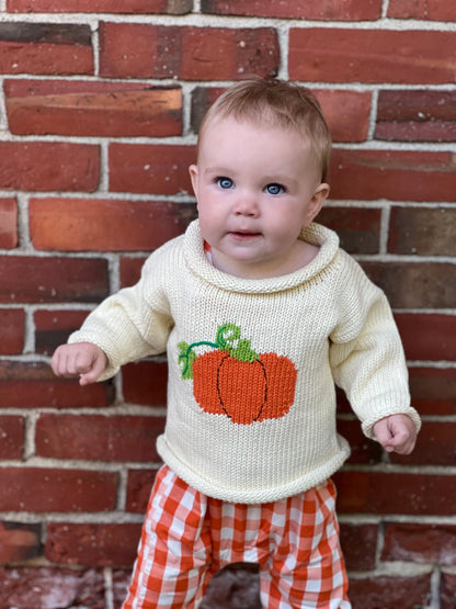 baby wearing sweater and orange gingham coveralls