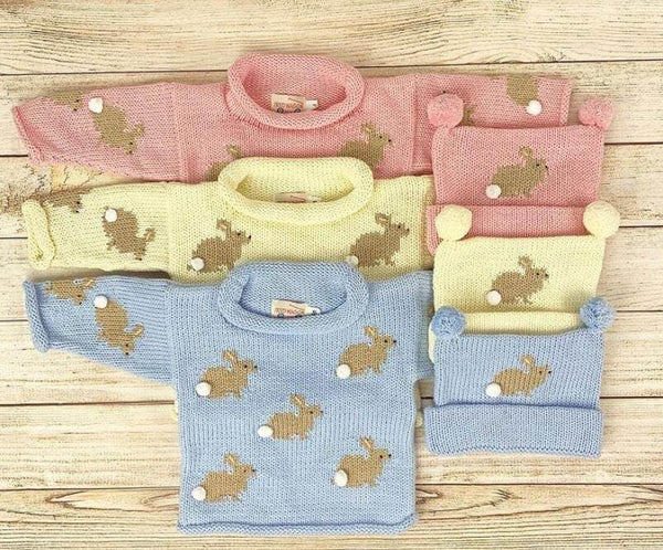 pink, blue and ivory bunny sweaters laid out with matching bunny hats