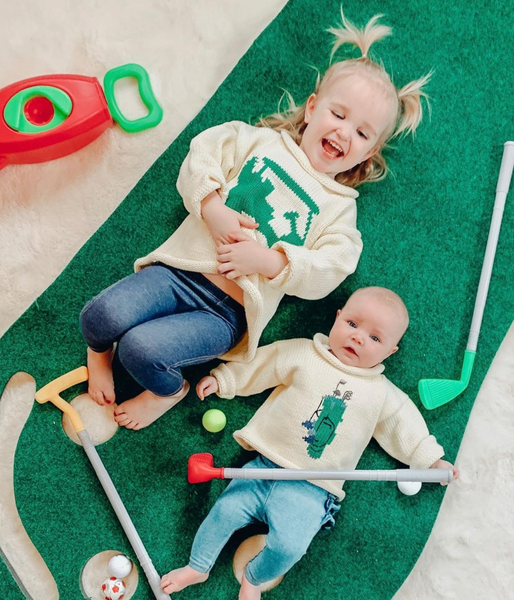 toddler wearing Golf Cart sweater and baby wearing Green Golf Bag sweater
