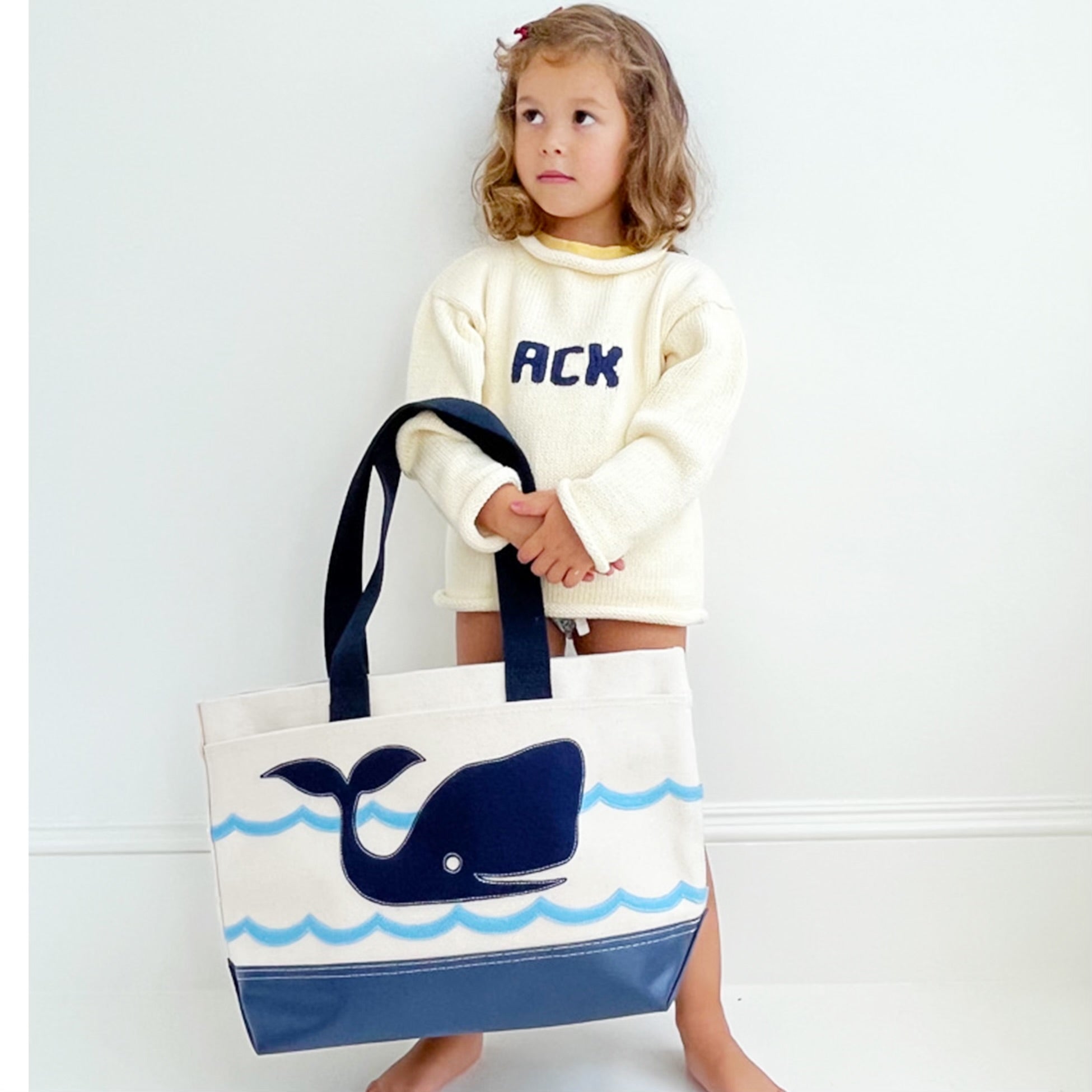 girl wearing ACK sweater with whale tote bag