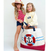 girls one wearing sweater and one wearing striped top and shorts, with anchor tote bag