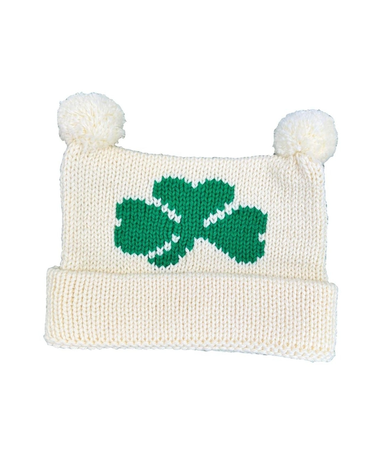 ivory hat, bottom is rolled up once with two poms at top, one green shamrock knitted in center