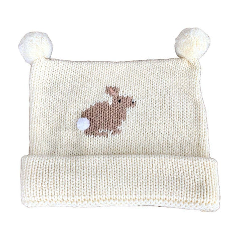 ivory knit hat with tan bunny in the center with white pom as tail, two ivory poms at top, bottom of hat is rolled up once