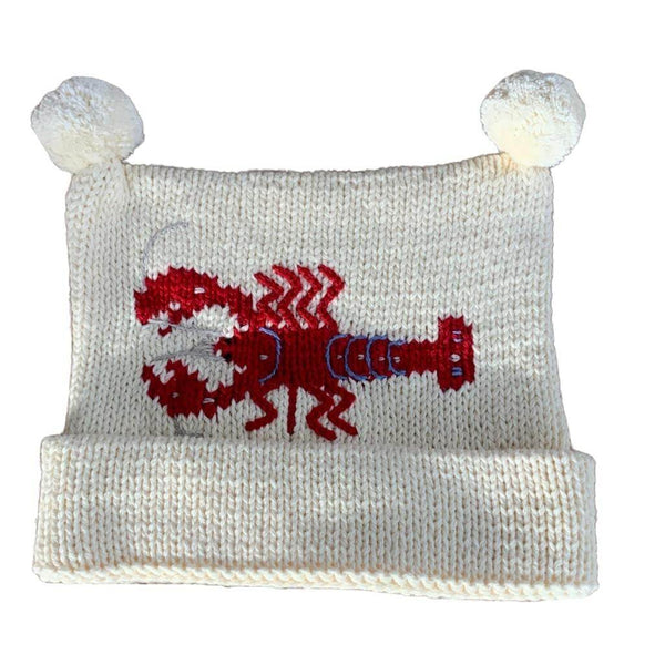 ivory knit hat with red lobster in the center with two white poms at top and bottom of hat is rolled up once