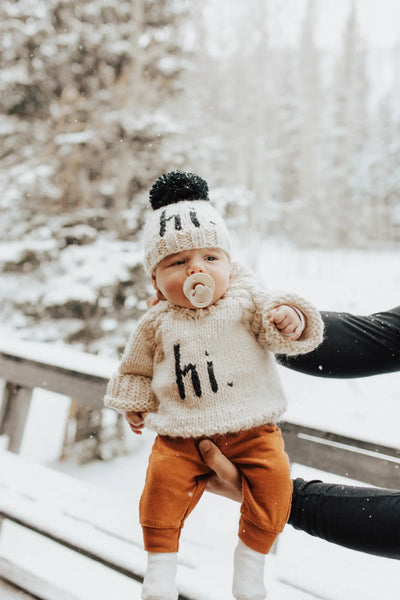 baby in snow wearing hi beanie 
