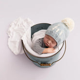 baby in bucket wearing blue hi beanie