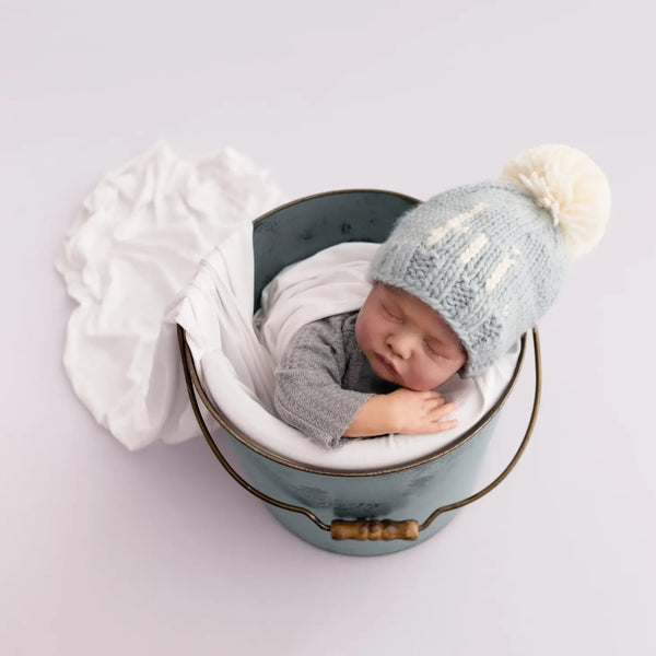 baby in bucket wearing blue hi beanie