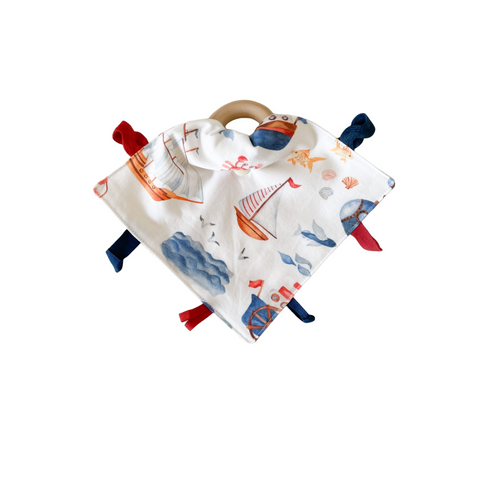 lovey blanket with designs of ships and waves with red and blue tags