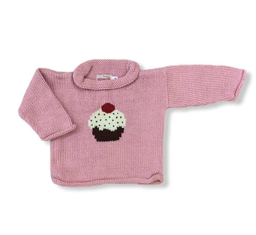 pink roll neck sweater with cupcake on front center, cupcake has brown bottom with white icing with brown sprinkles and red cherry on top