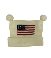 ivory hat with bottom rolled up once and poms at top, red white and blue flag in center