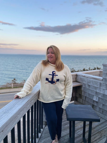 woman wearing the adult version of the Ivory Anchor Rope Roll Neck sweater with beach background