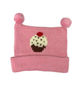 pink hat rolls up once at bottom, two pink poms at top, in center white and brown cupcake with red cherry on top