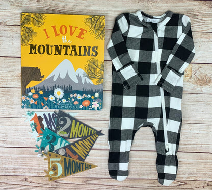 black and white buffalo check footie with milestone pennants and book 