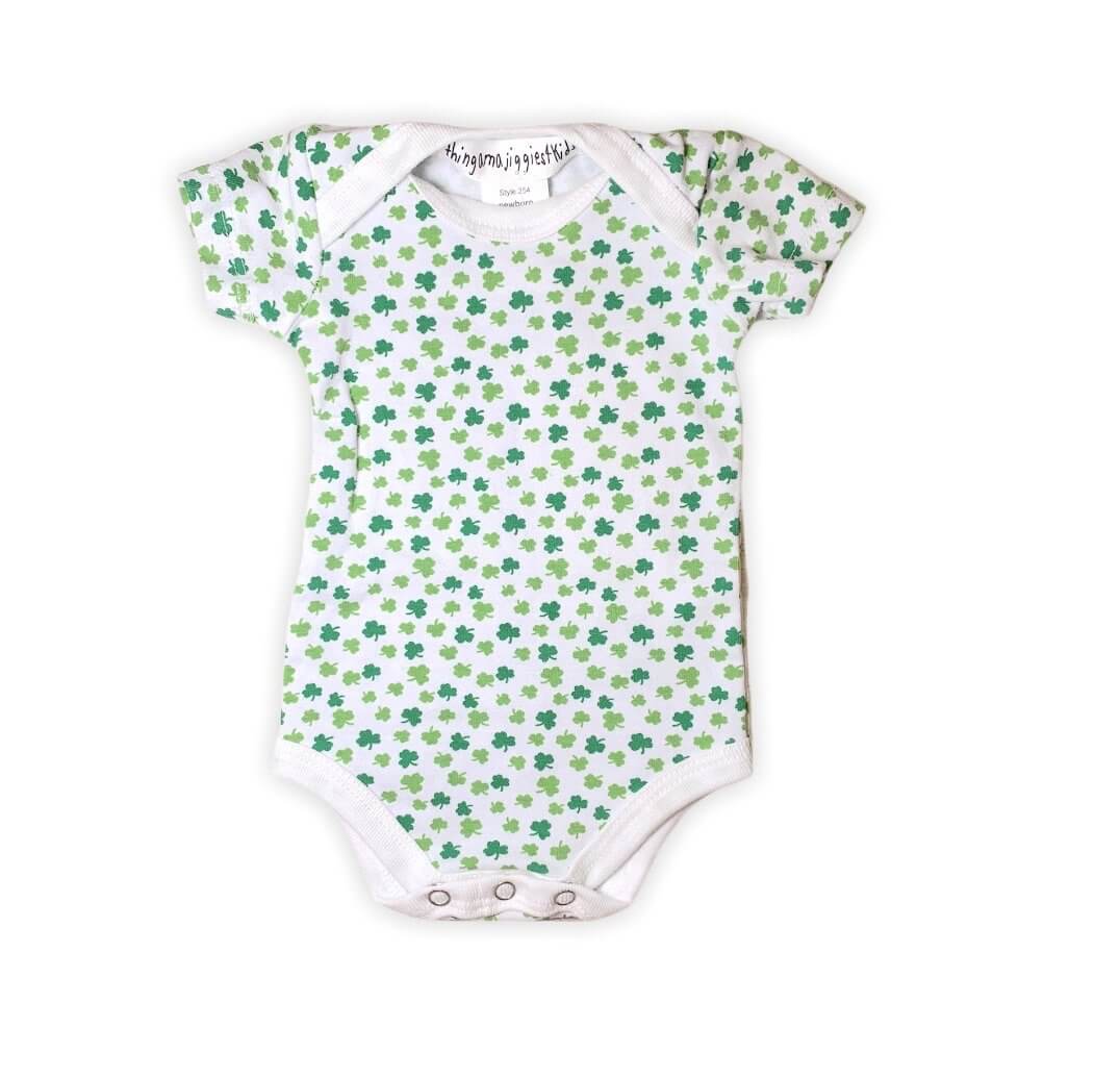 white onesie with shamrocks of different shades of green all over, white hem on bottom and neckline