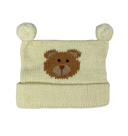 ivory hat with two poms at top, hat is rolled up once. In the center there is a brown teddy bear face with lighter ears and nose