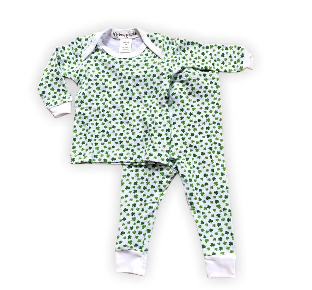 white pajamas with tiny green shamrocks in varying shades of green, white cuffs on ankles and arms with white trim on collar