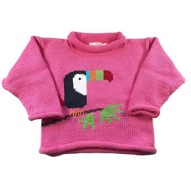 pink roll neck sweater with toucan bird sitting on a branch with two green leaves, toucan has a red, green, orange and blue beak