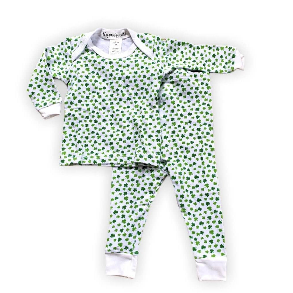 white pajamas with tiny green shamrocks in varying shades of green, white cuffs on ankles and arms with white trim on collar
